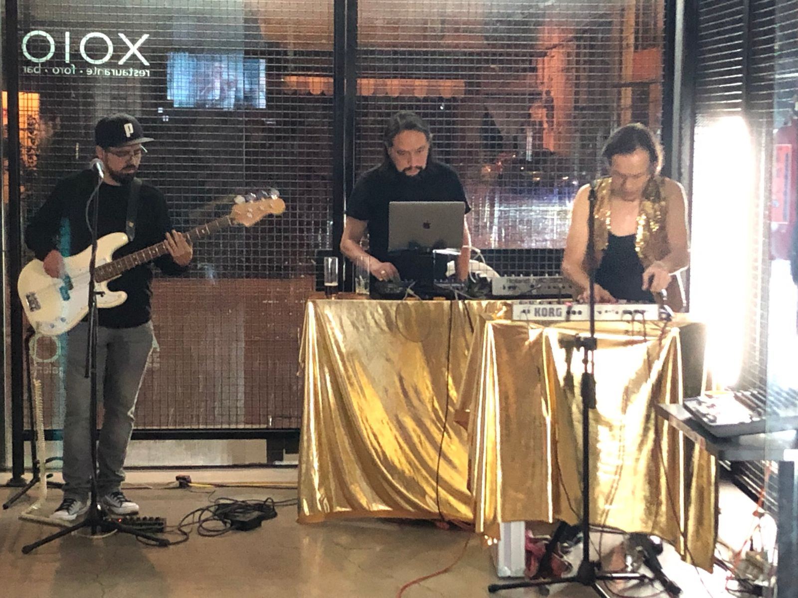 El trío en vivo en Xolo, con mesas forradas de lamé dorado